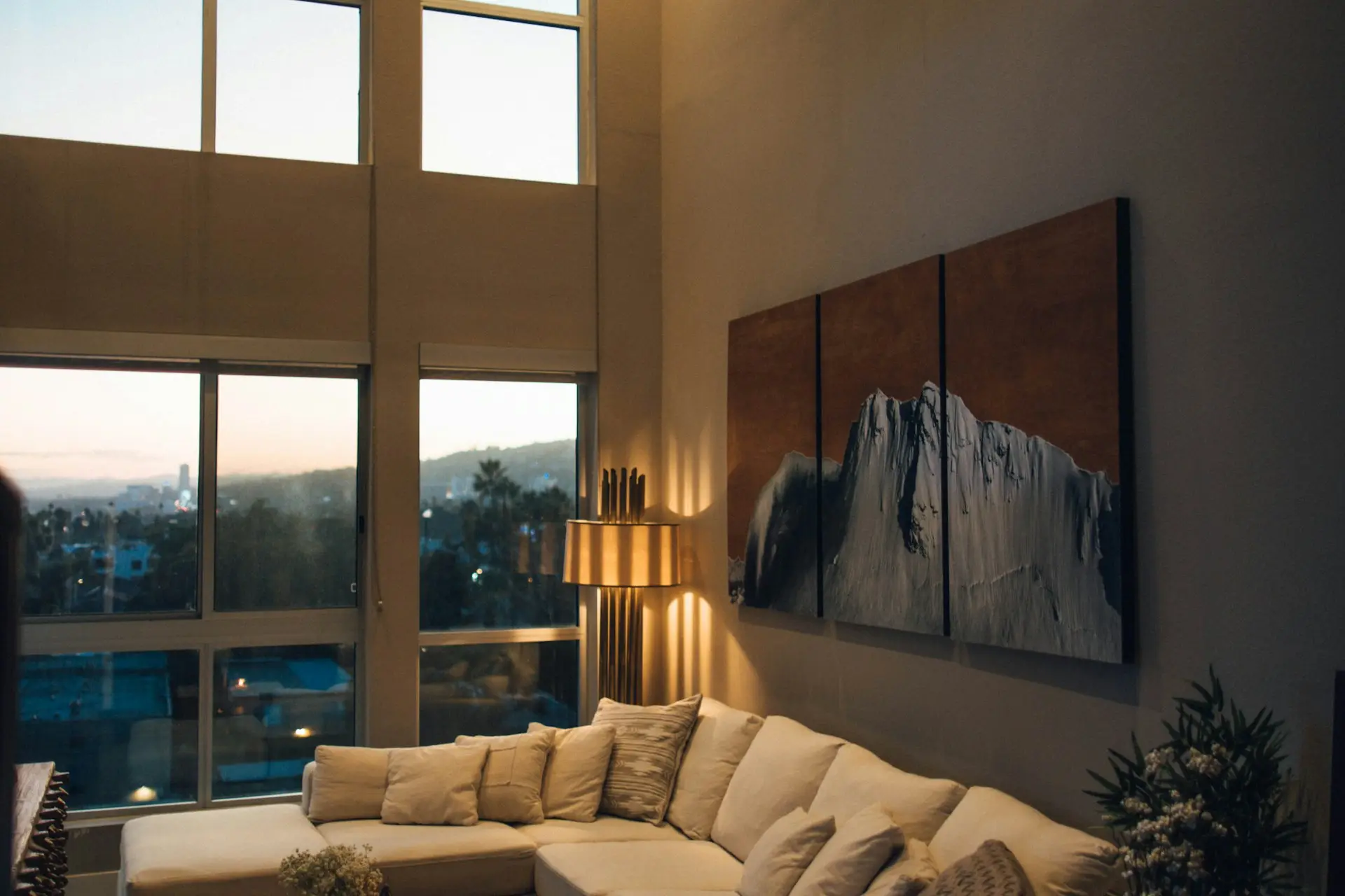 Modernes Wohnzimmer mit raumhoher Verglasung und warmem Licht in der Abenddämmerung